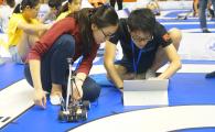 Two students from the 4-member First Class Award-winning team prepare their smart car in the competition.	