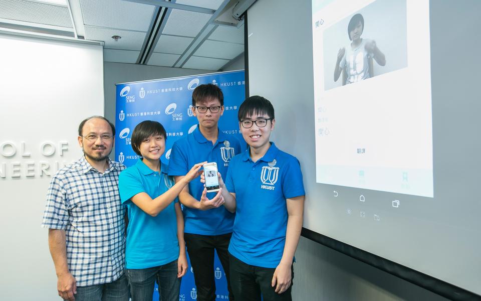 (from left) HKUST’s Prof Brian Mak and students Mary Leung, Kelvin Yung, and Ken Lai show their app on the mobile phone.