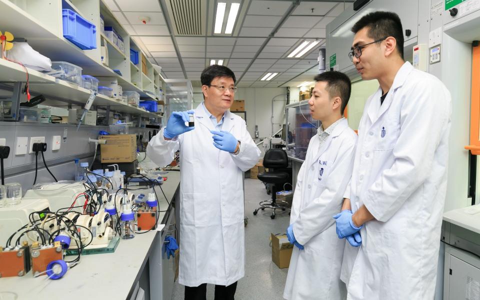 Prof. Zhao Tianshou (left) shows a sample of the e-fuel to his team members.