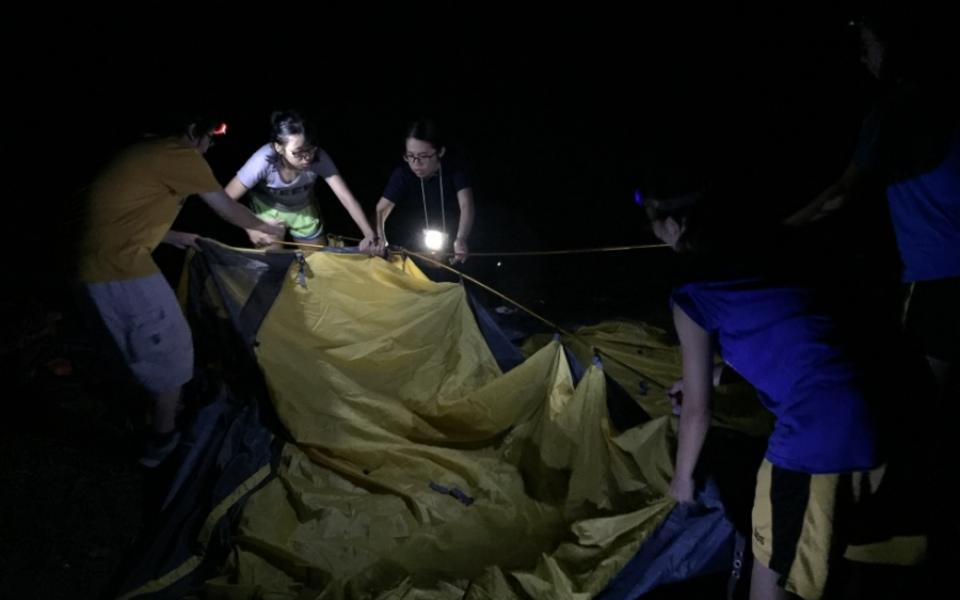 Students set up tents in the dark