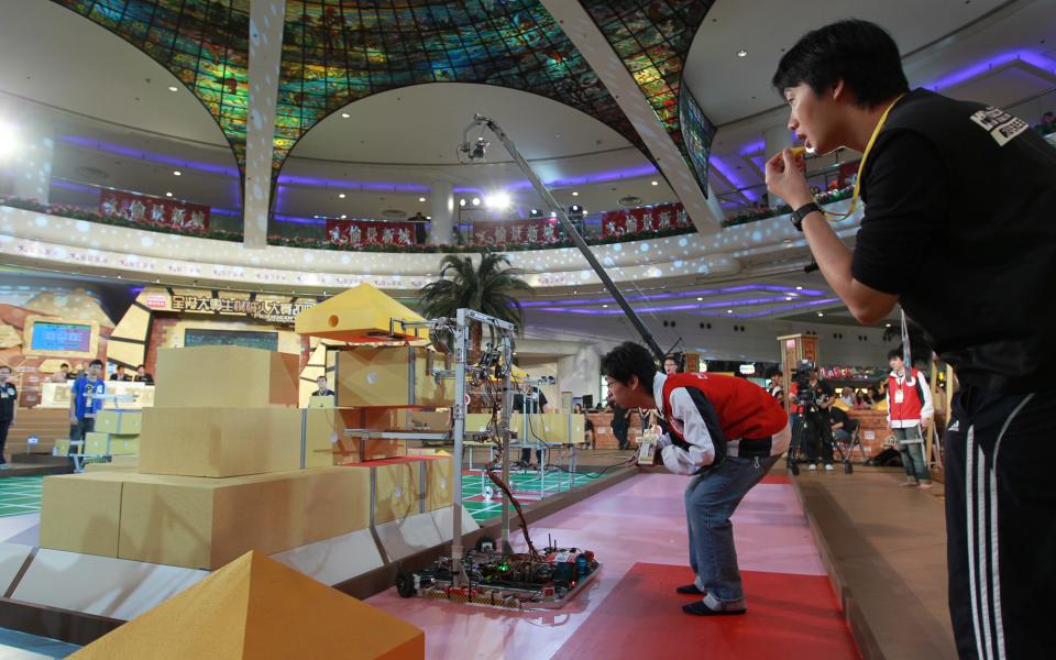 A member of “Fiery Dragon” is operating the robot to position the blocks of a pyramid during the contest