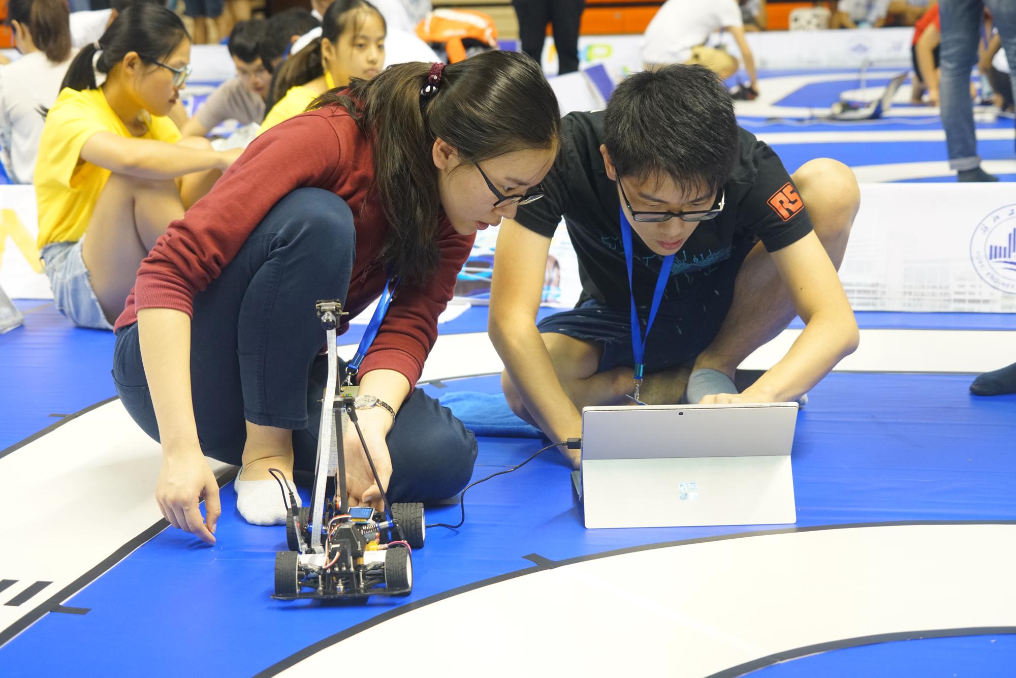 Two students from the 4-member First Class Award-winning team prepare their smart car in the competition.	